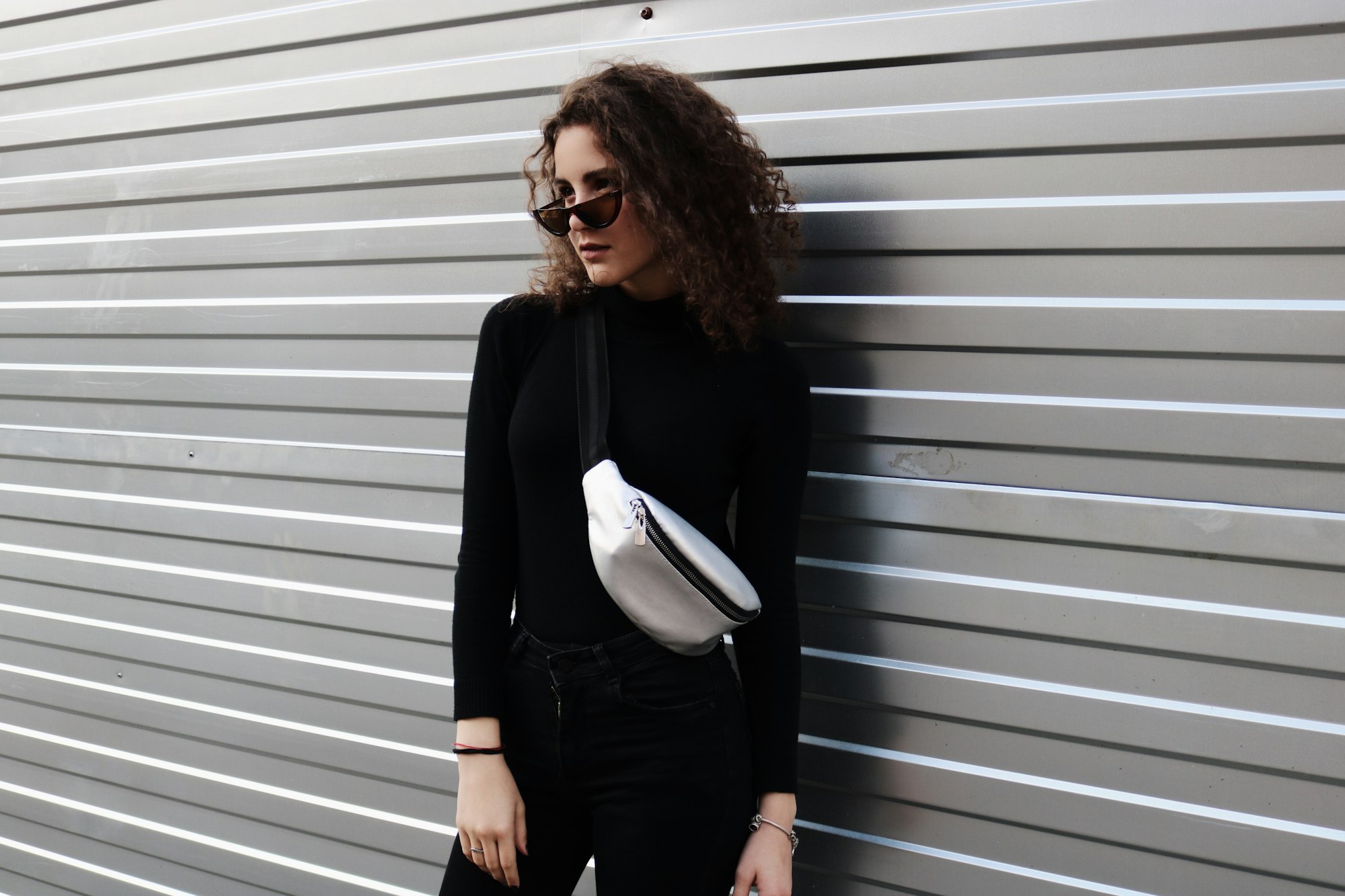 Woman wearing all black with white crossbody bag