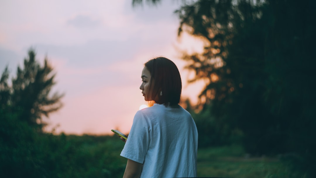 silhouette photography of woman standing near tree