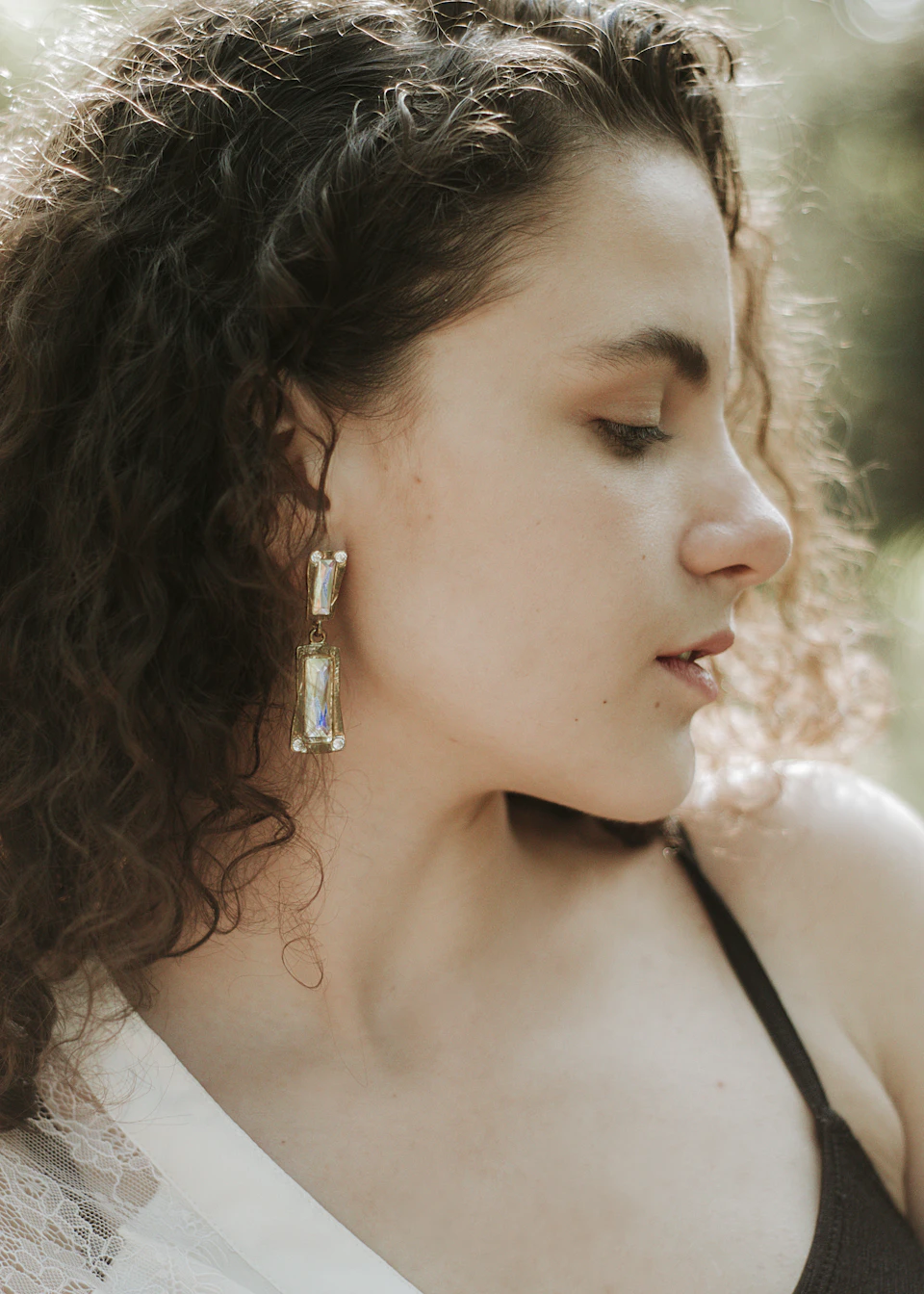 Woman's face in close-up view with loose curls hair and large metal earrings
