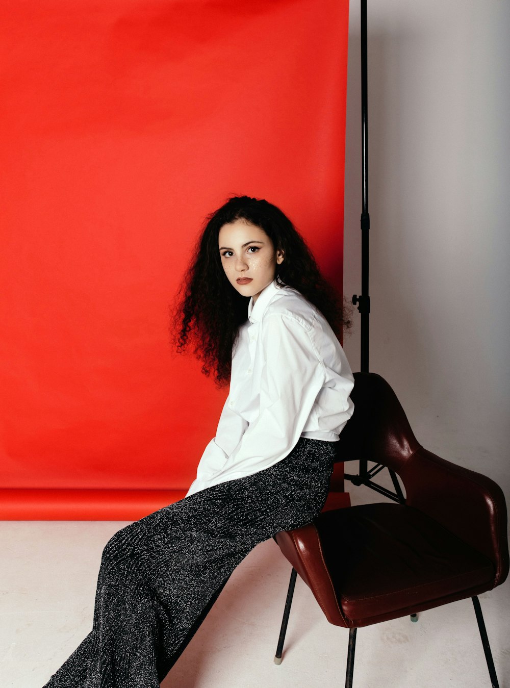 sitting woman wearing white long-sleeved shirt near orange tarpaulin