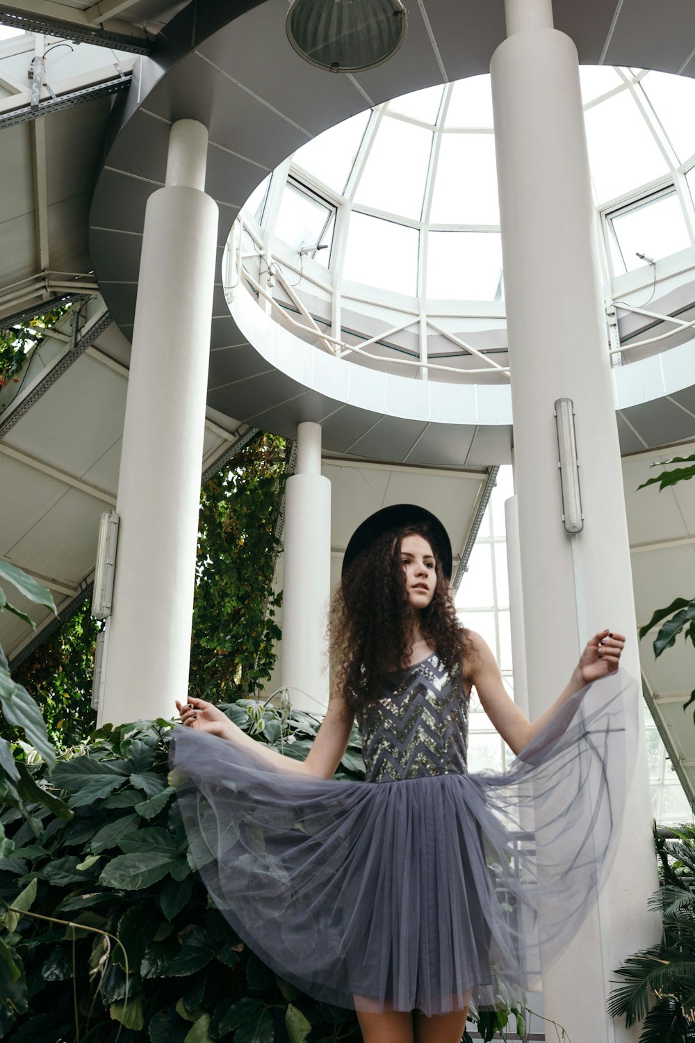 woman in gray sleeveless dress wearing black hat under white dome