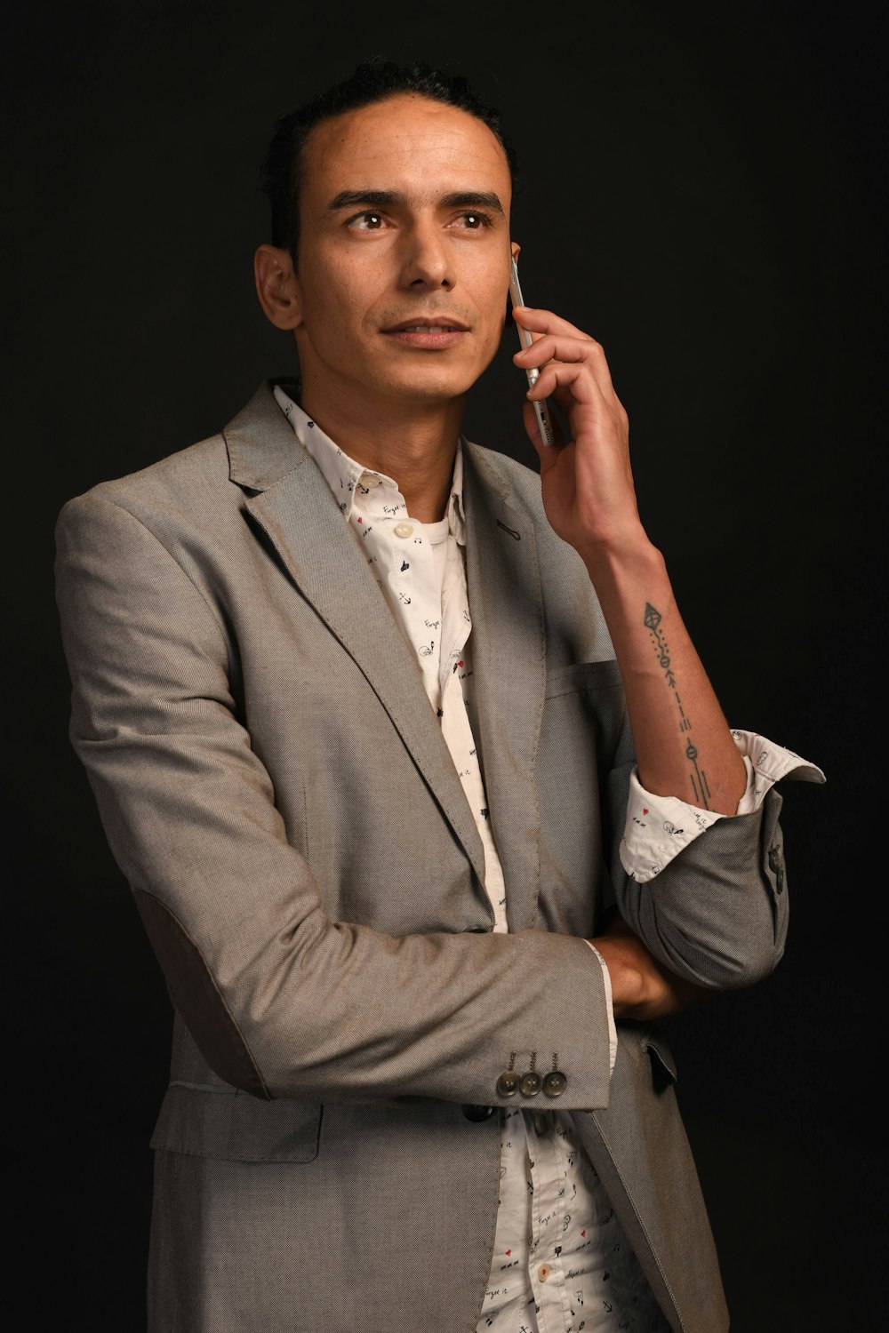 man wearing grey notched lapel suit jacket taking phone calls