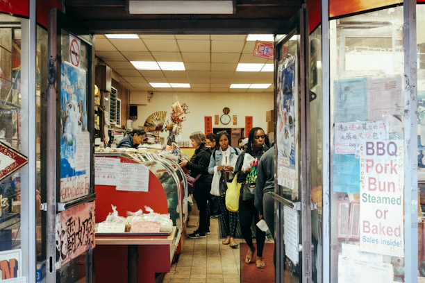 Warm, inviting shop interior with shelves filled with colorful oriental sweets and friendly staff assisting customers.