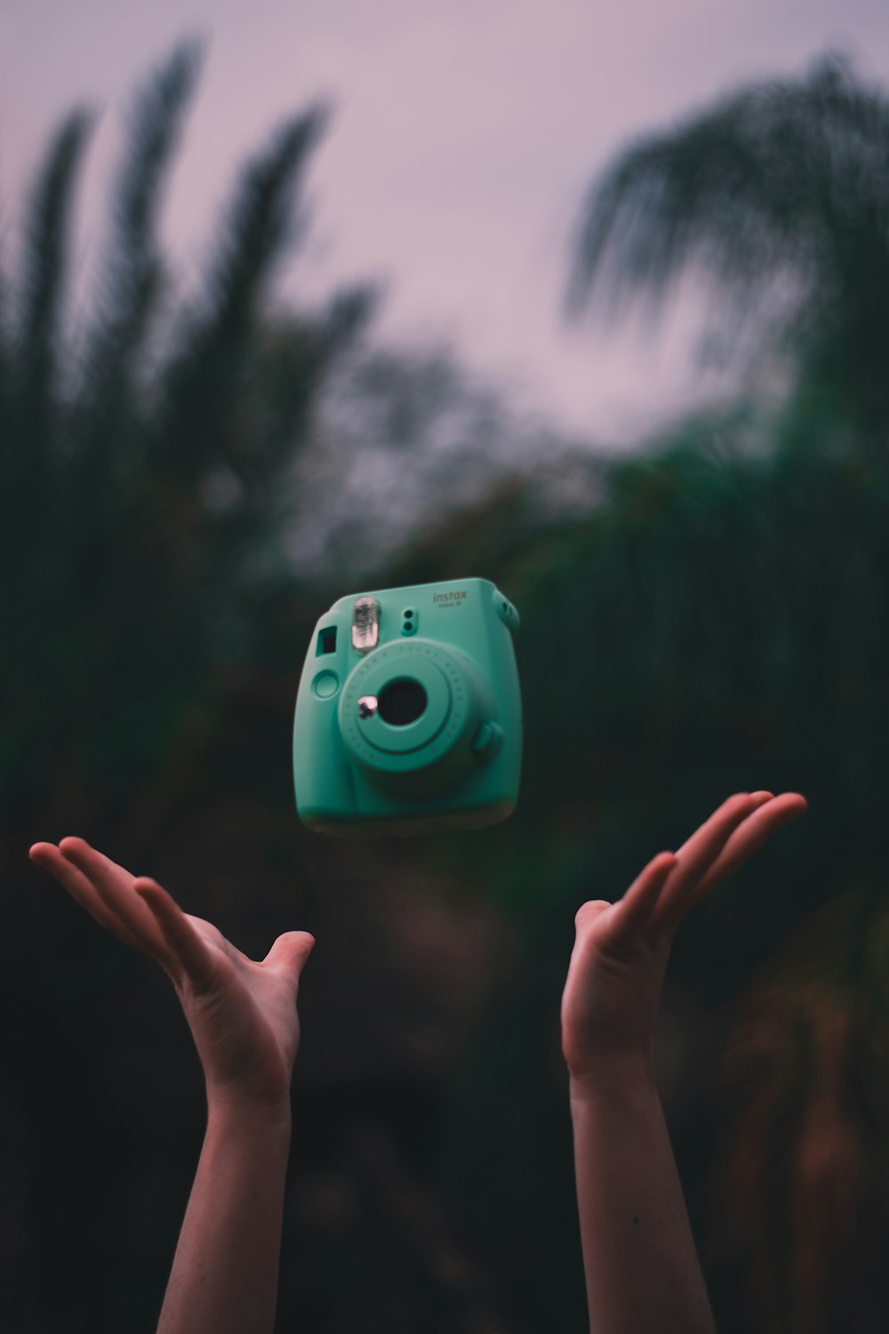 person throwing green Fujifilm Instax camera