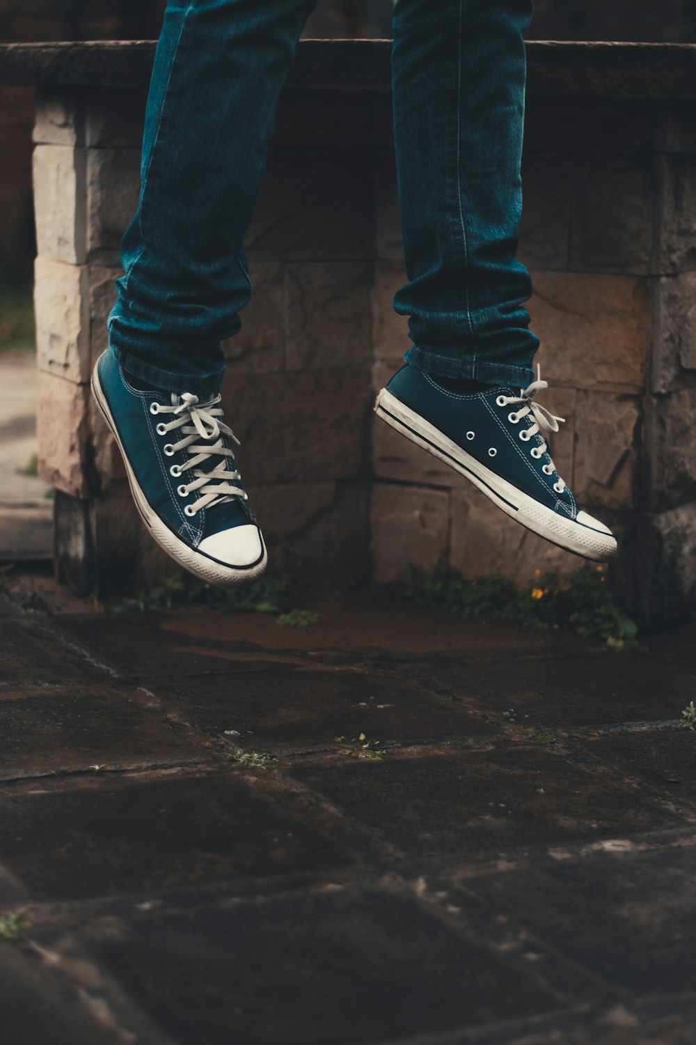 person wearing pair of black low-top sneakers while jumping