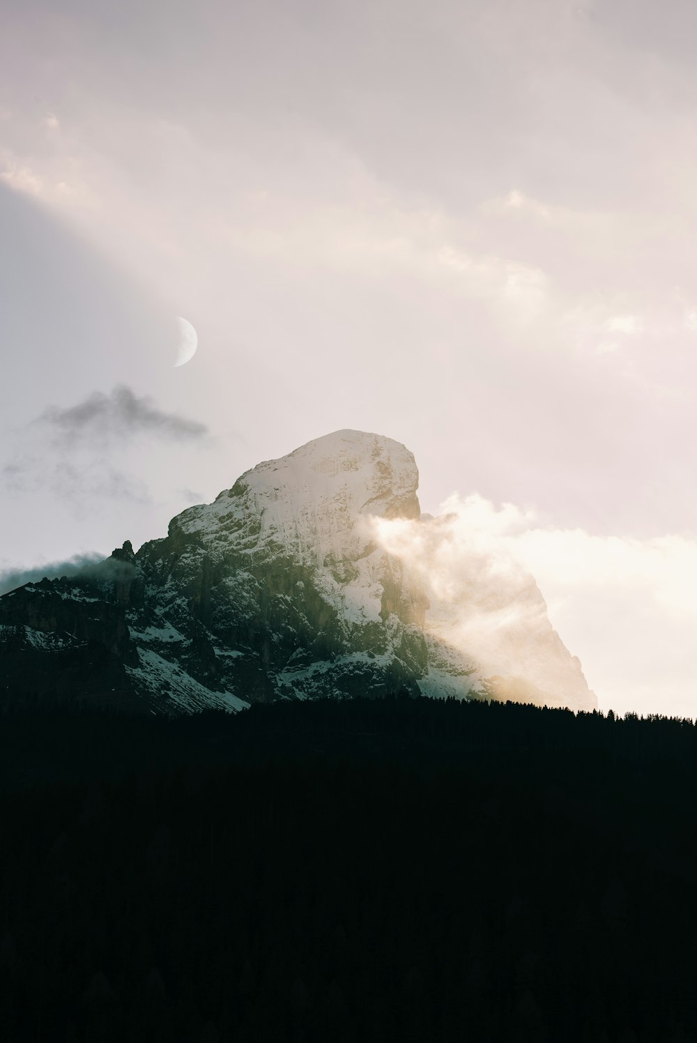 a mountain covered in snow under a cloudy sky