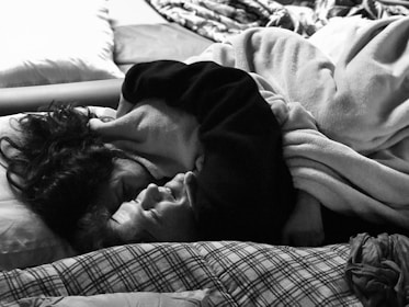 A cozy indoor setting with two people sharing a blanket and smiling before a nap.