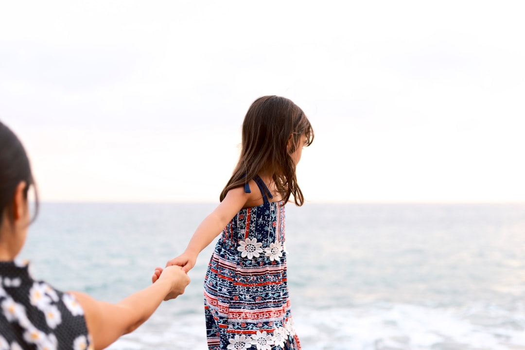 girl holding girl overlooking body of water at daytime