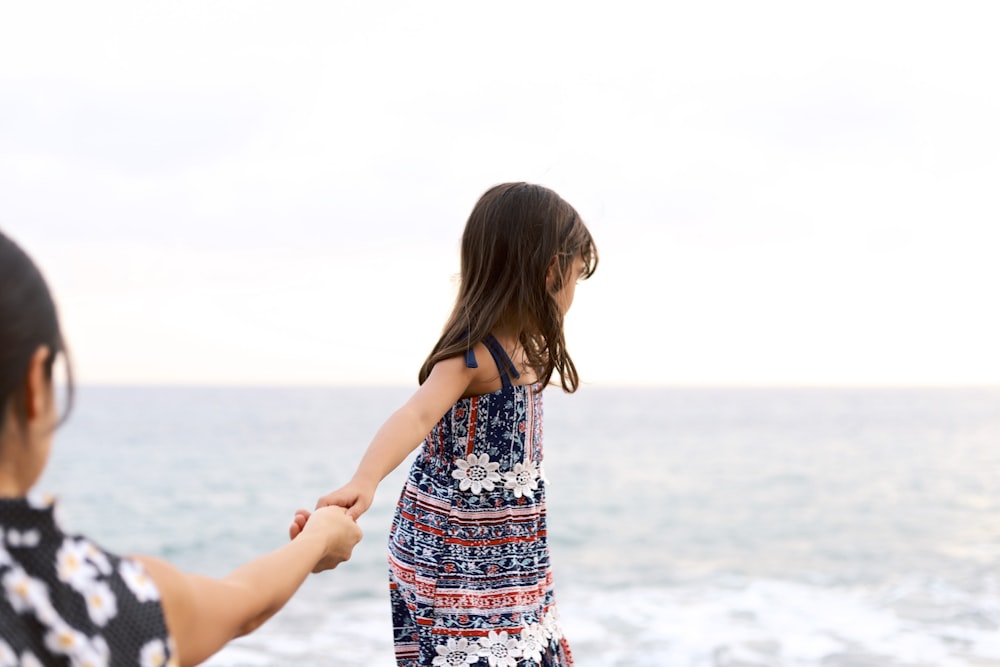 girl holding girl overlooking body of water at daytime