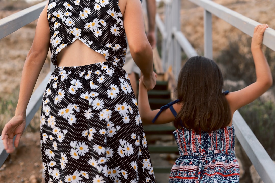 woman and girl walking on wooden stair during daytime