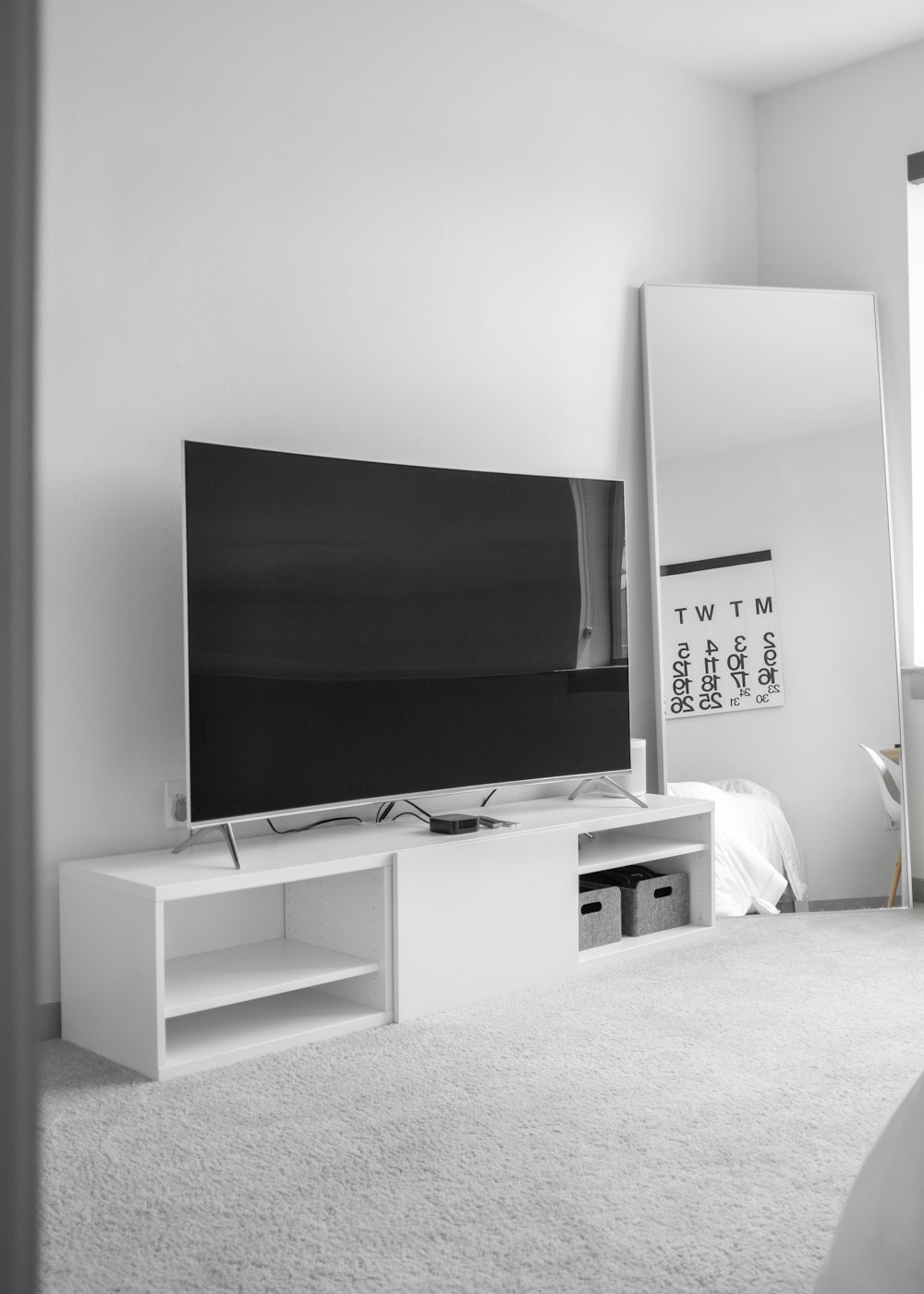 grauer Flachbildfernseher auf weißem TV-Ständer