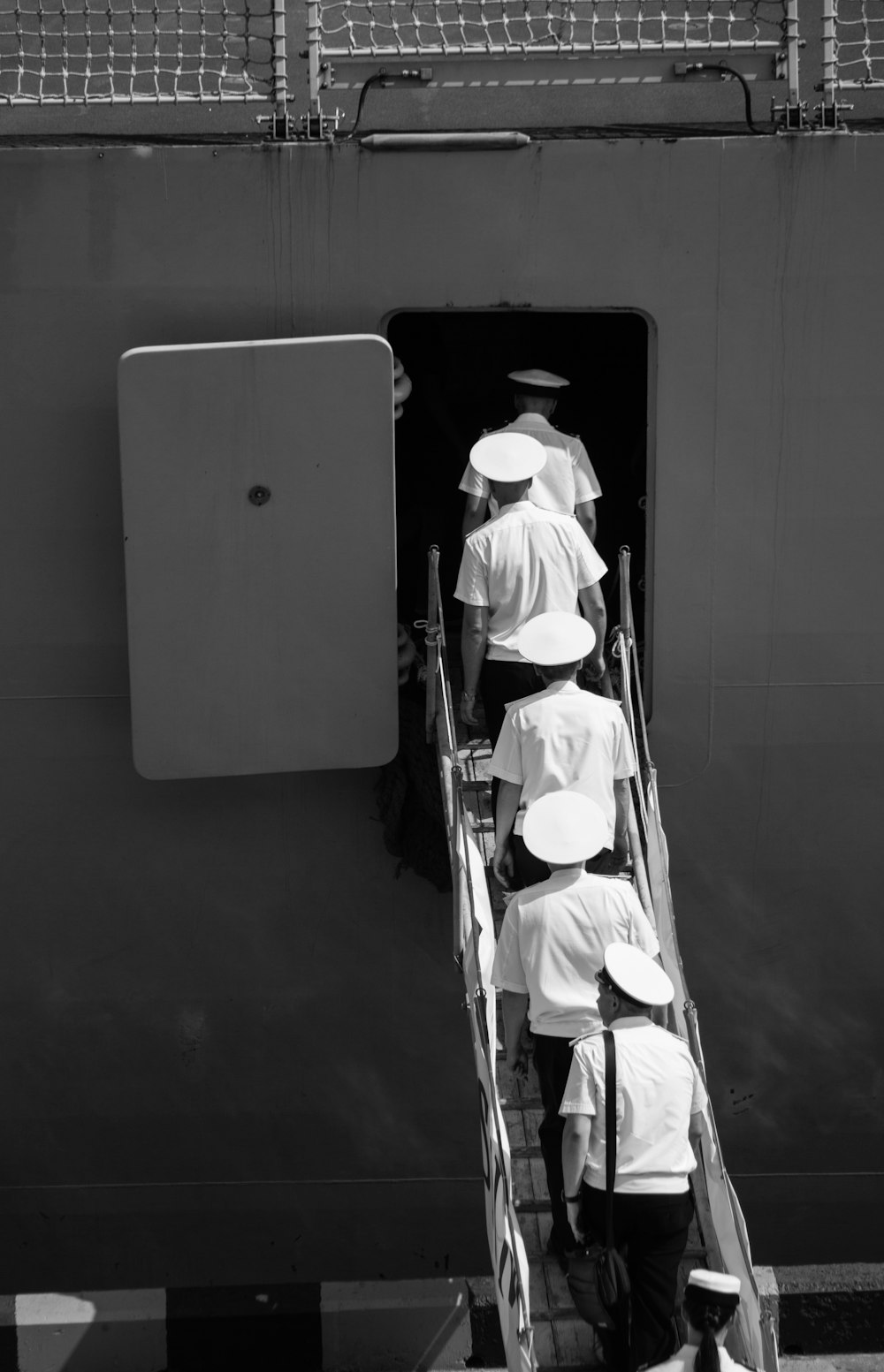 Personas en uniforme subiendo en las escaleras del avión en fotografía en escala de grises