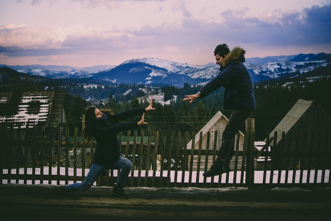 man in blue jacket jumping away to the woman kneeling on the ground