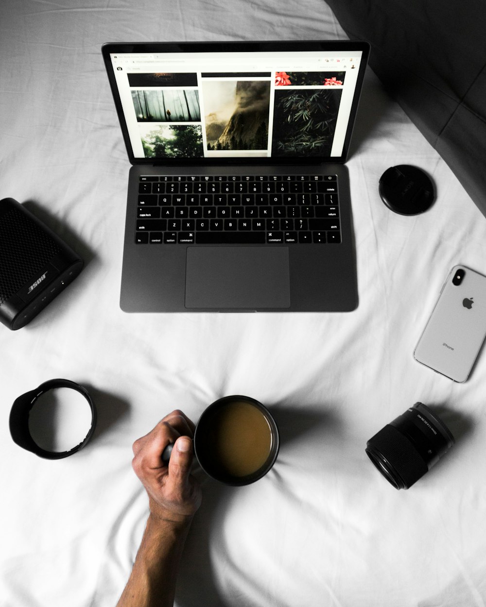 a person holding a cup of coffee in front of a laptop