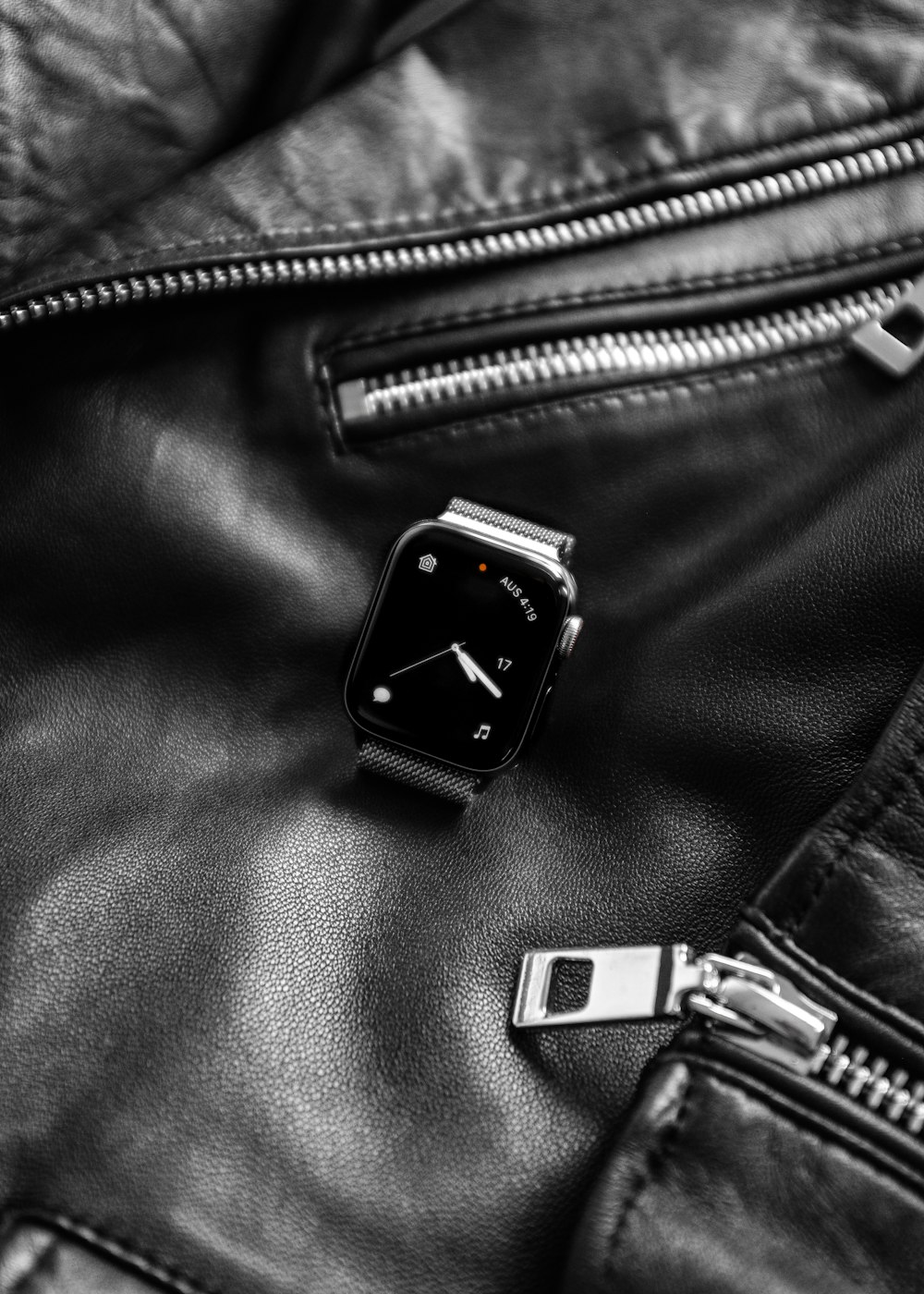 black smartwatch on top of black leather jacket