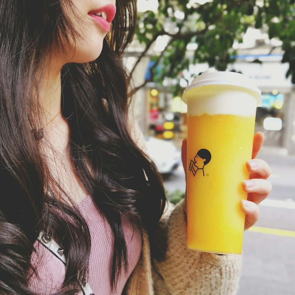 woman holding white disposable cup