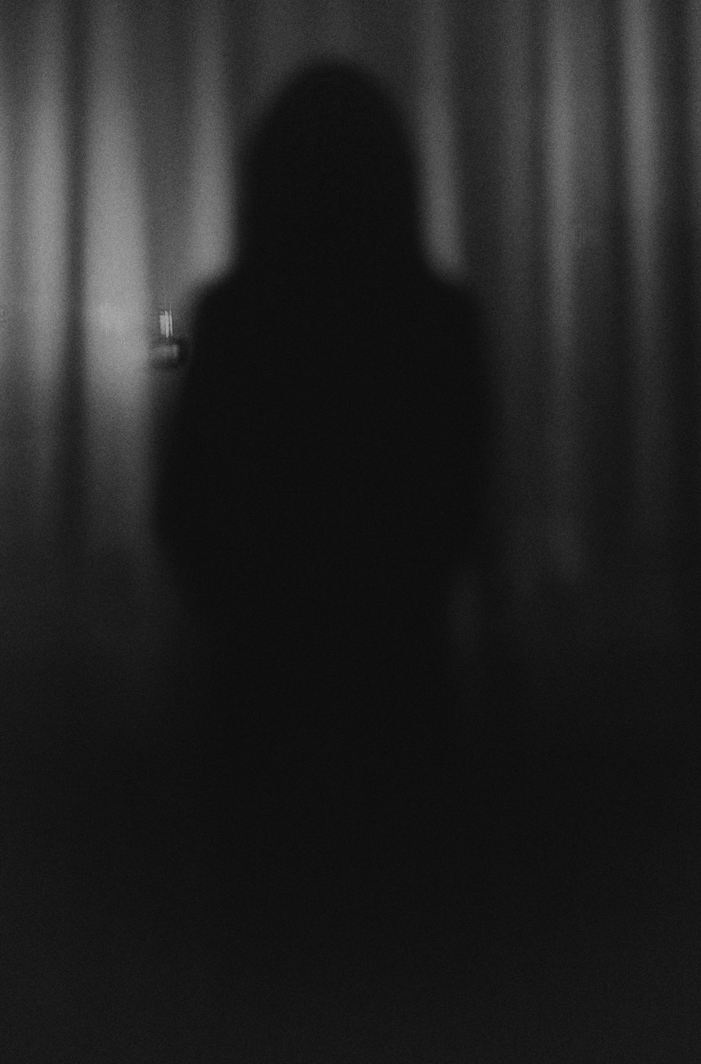 Una persona in piedi davanti a una tenda nel buio