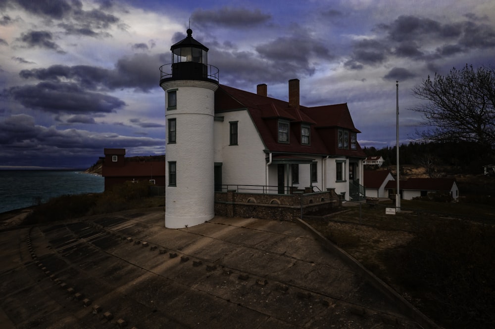 lighthouse and house near the ocean during day