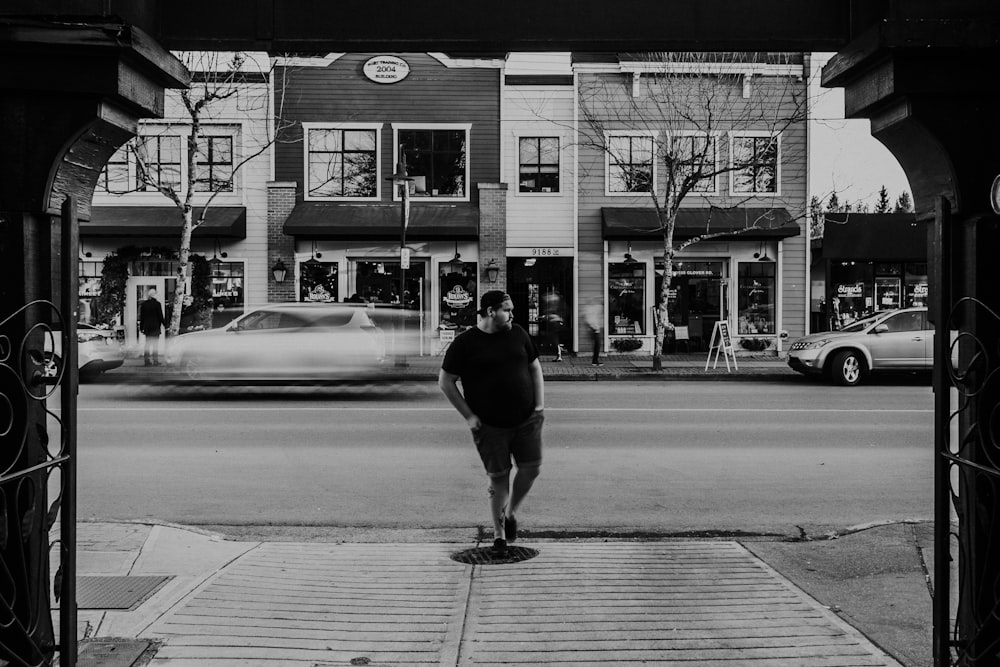 greyscale photography of man standing near building