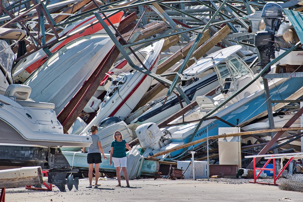a couple of women standing next to a pile of boats