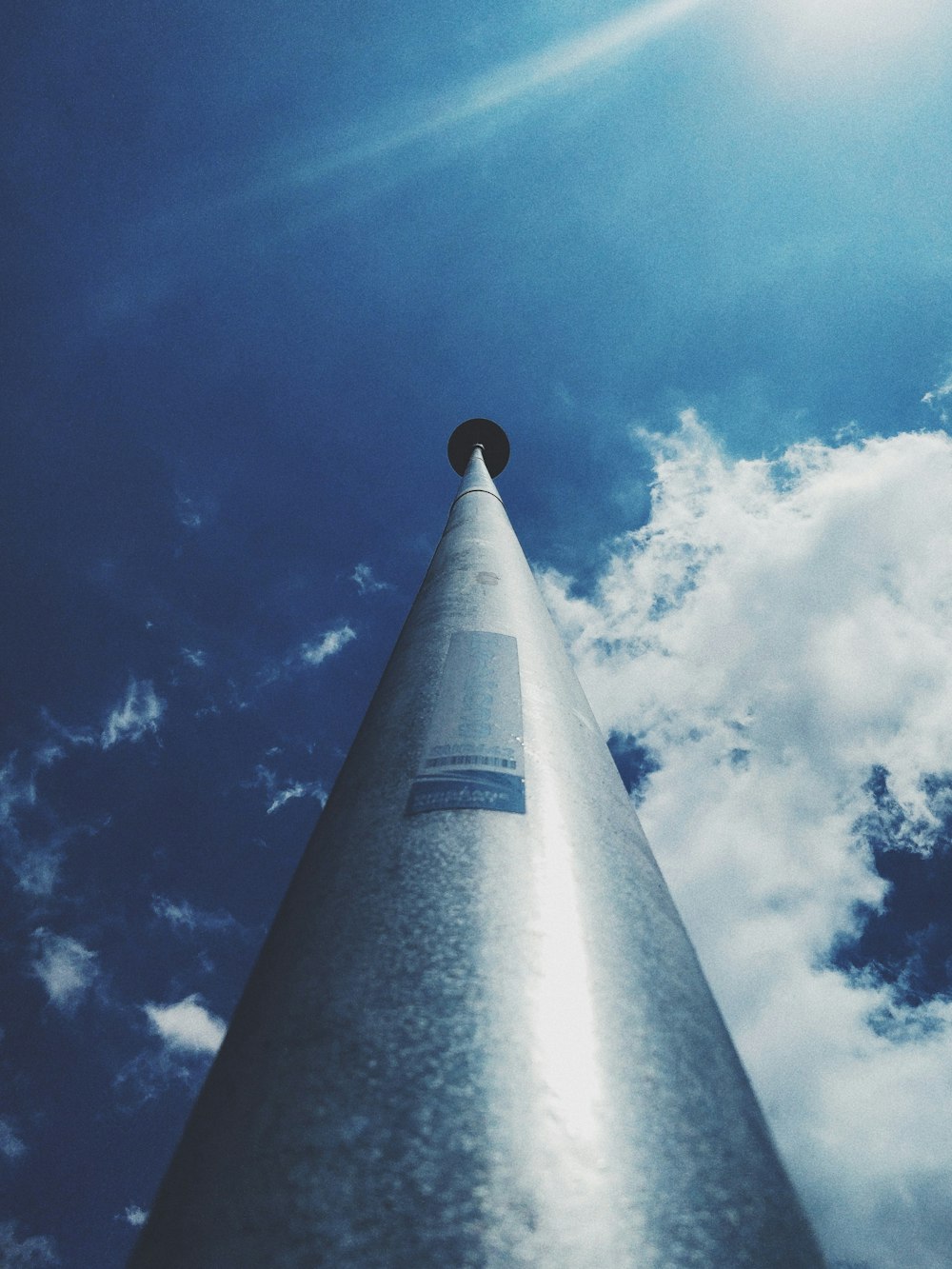 tall grey metal pole under blue and white cloudy sky