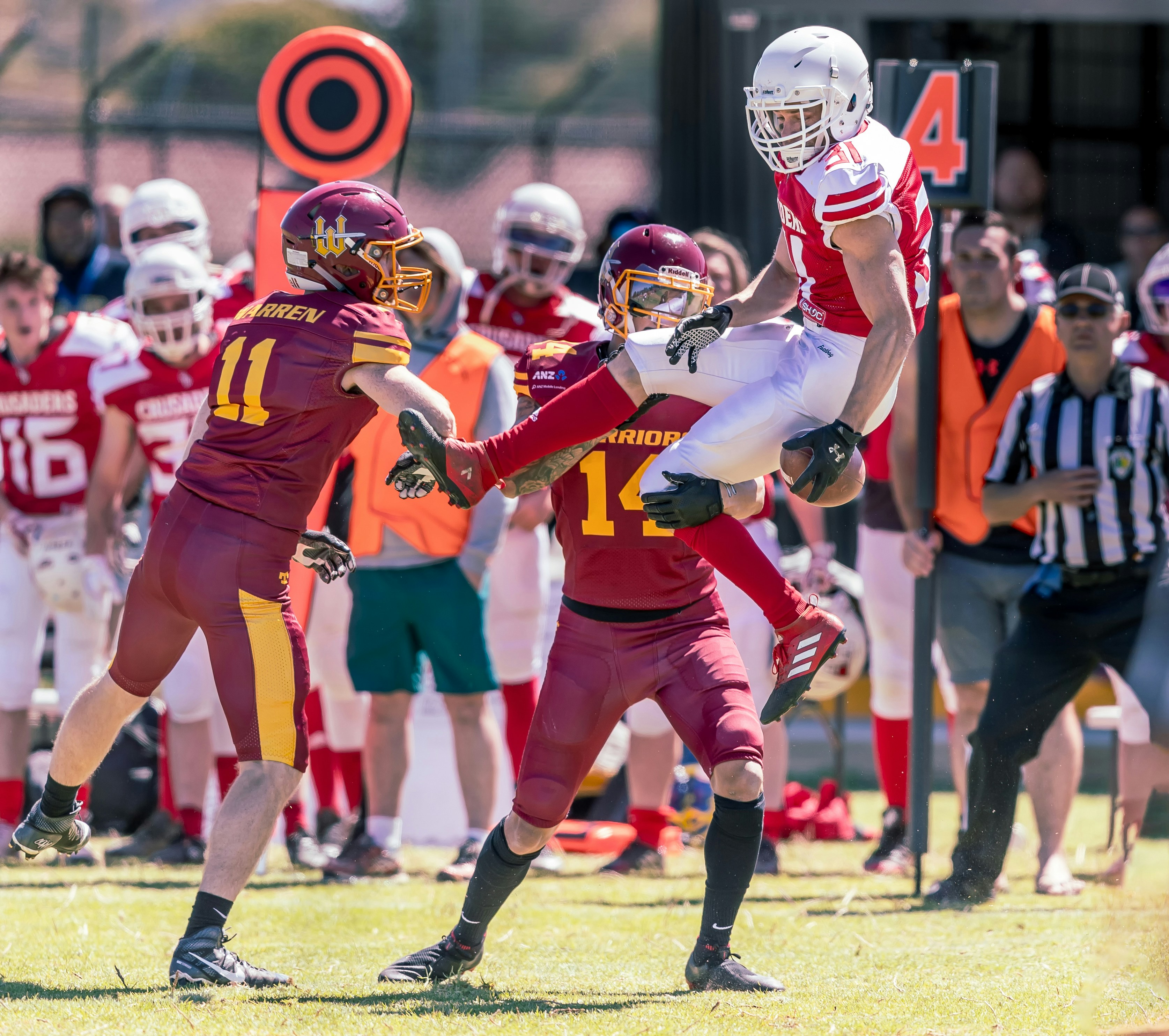 American Football player about to land beside other player attempting to snatch the ball on field