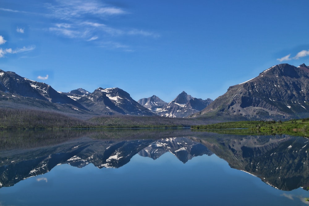 Montanha cinzenta e branca perto do lago calmo durante o dia