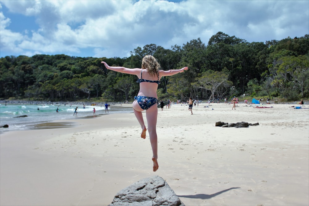 woman in bikini jumping on shore