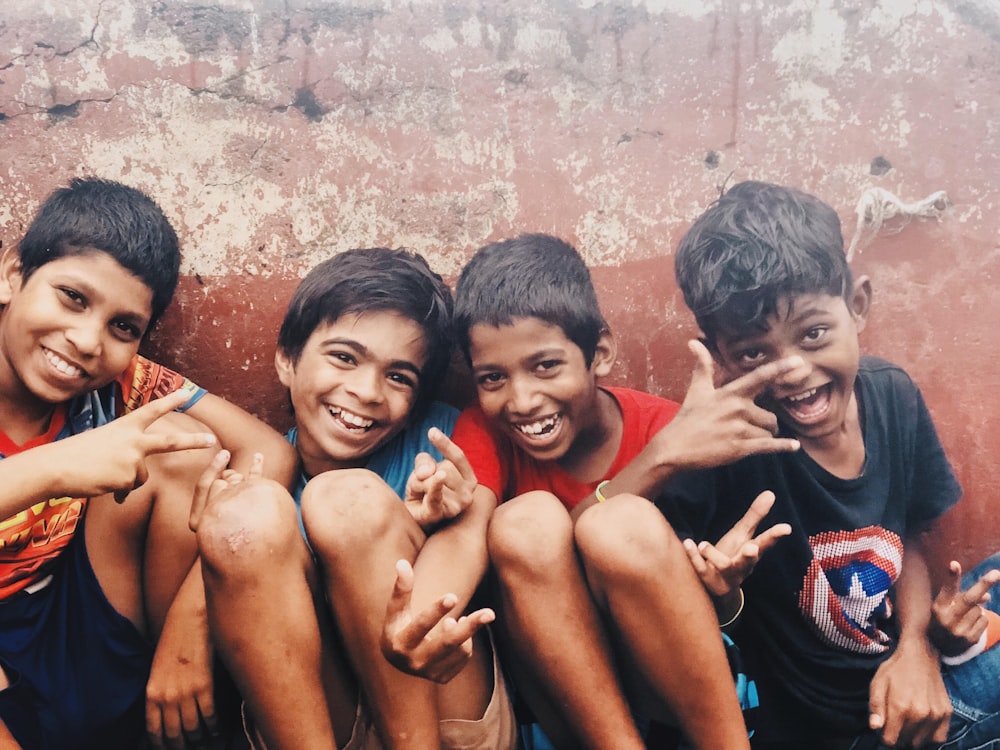 four kids sitting by the wall