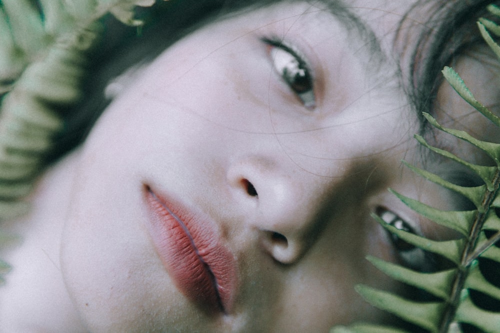 woman in red lipstick with linear leaves beside her