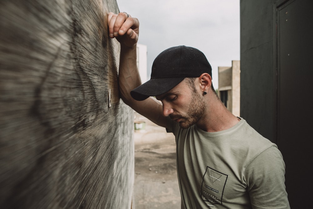 man in gray and black crew neck shirt leaning on gray wall