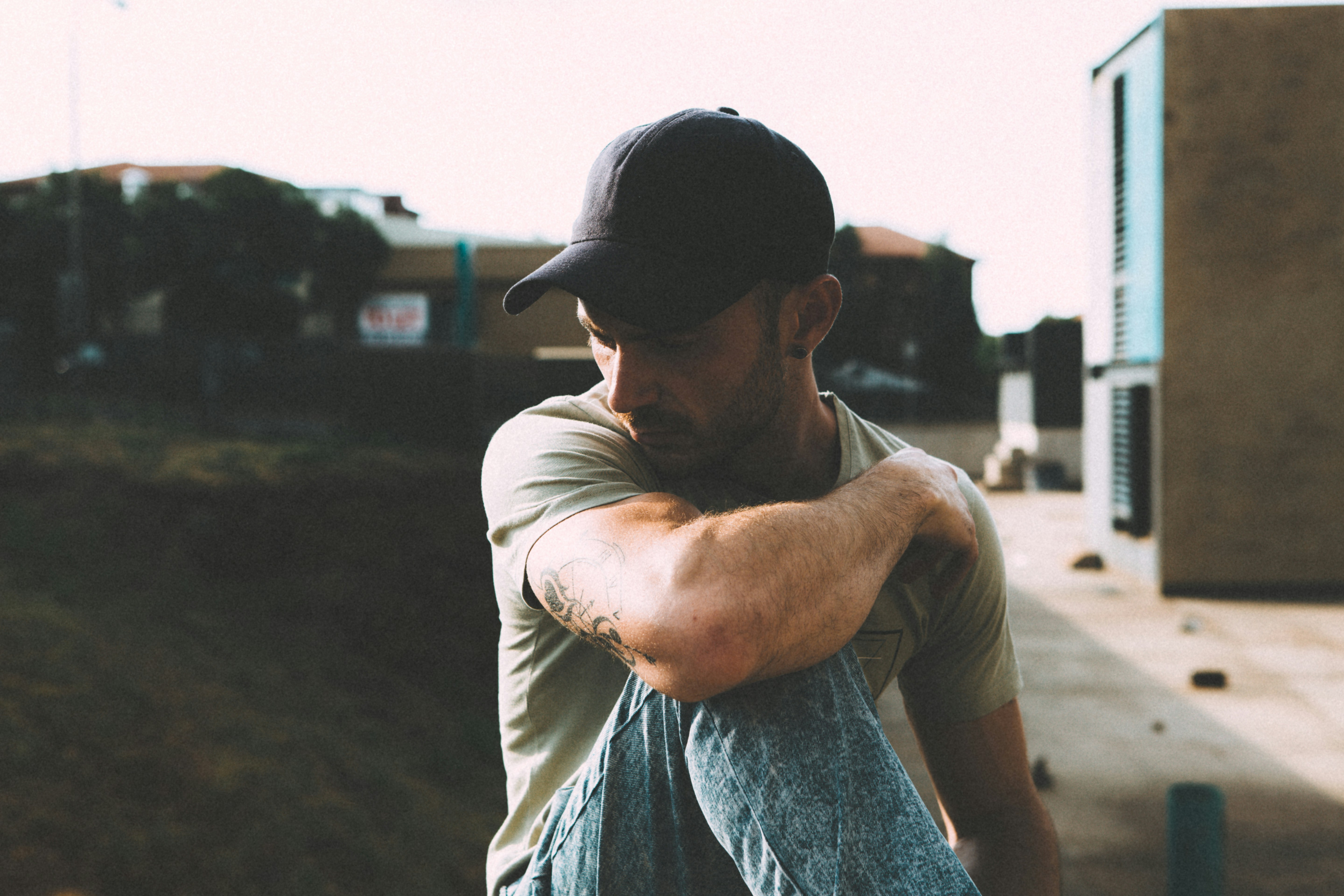 man in grey fitted t-shirt and denim jeans sitting and overlooking building