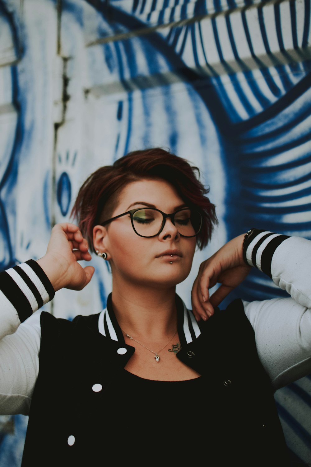 woman in eyeglasses and jacket posing while closing her eyes