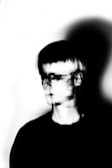 A black and white photograph depicting a person with a blurred, double-exposure effect, creating a sense of motion or distortion.
