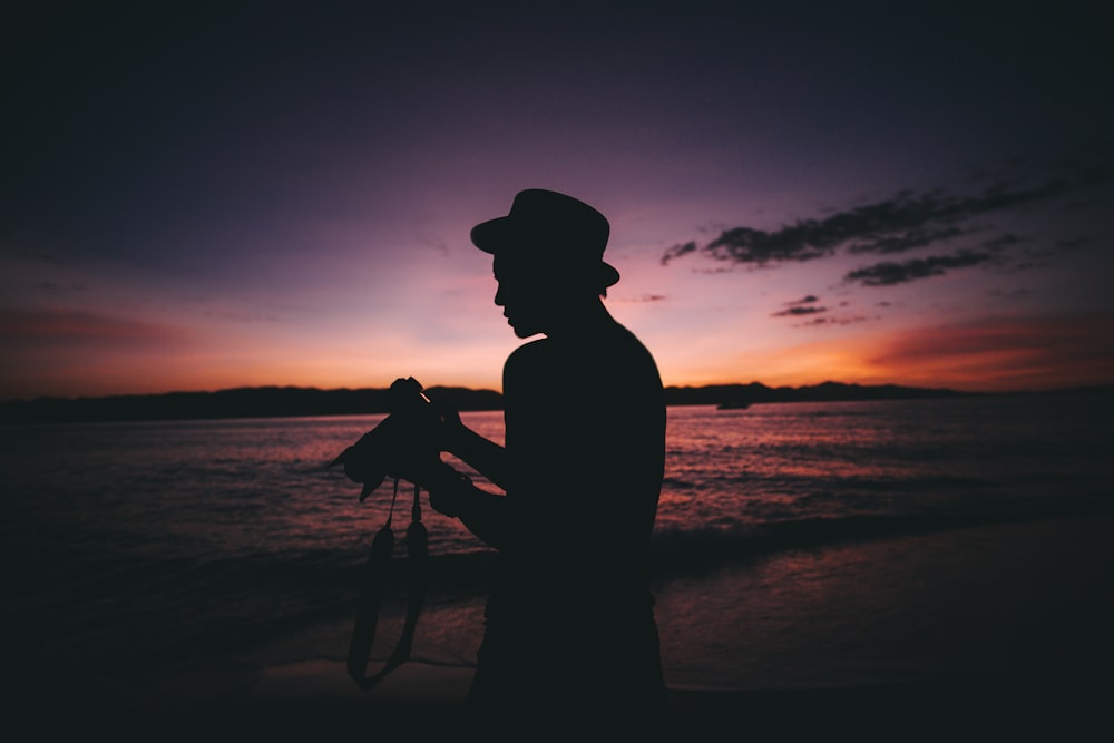 silhouette photography of man standing while holding DSLR camera