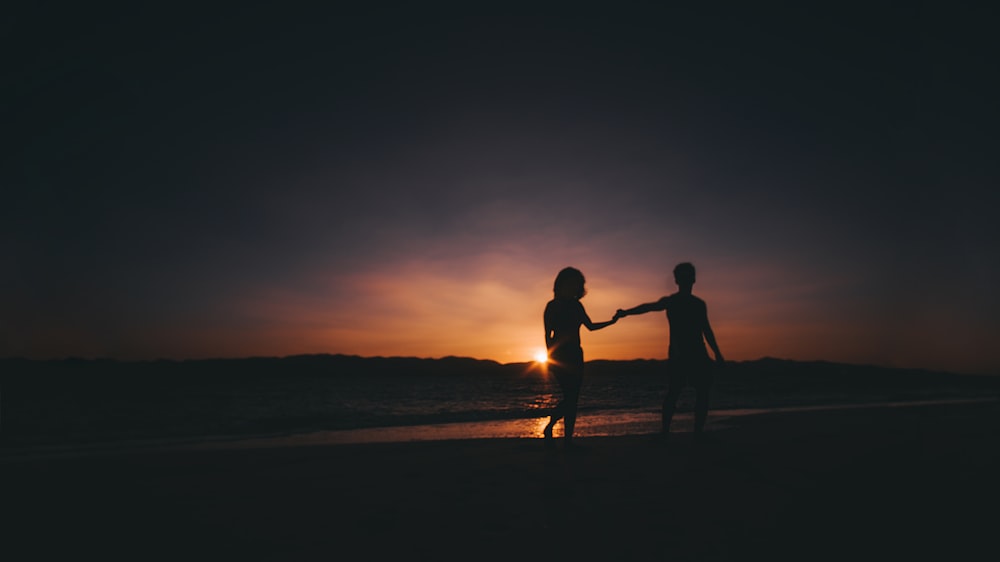 silhouette photo of couple beside sea