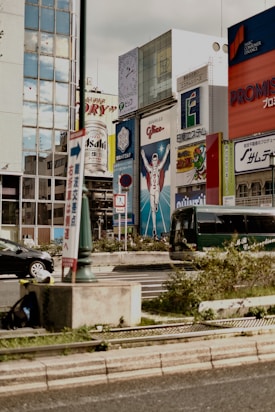 A bustling city scene with a large billboard featuring a triumphant athlete figure. Surrounding buildings showcase various advertisements, including ones for Asahi and other brands, against a backdrop of glass-clad structures.