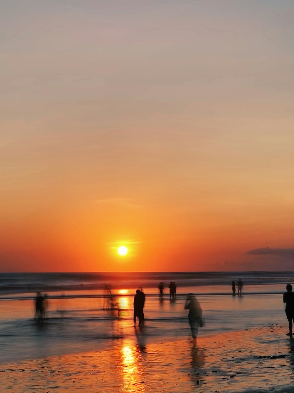 Gente en la playa durante la puesta de sol