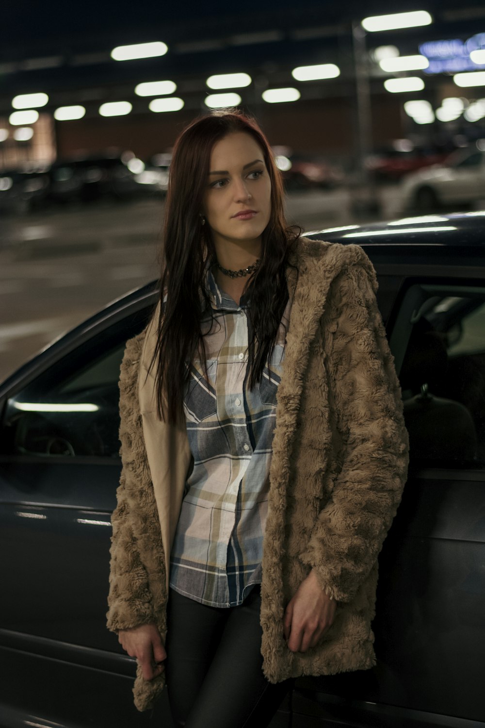 standing woman leaning on black car