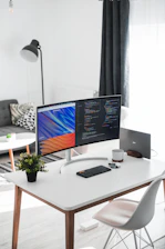 A sleek minimalist home office setup with a modern monitor, wireless keyboard, and subtle blue accents.