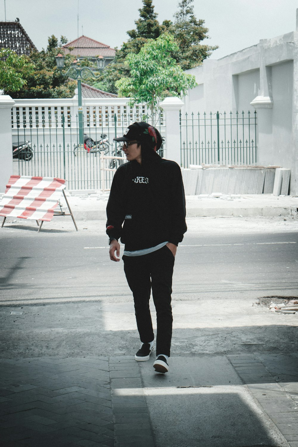 man wearing black hoodie standing on gray concrete pavement