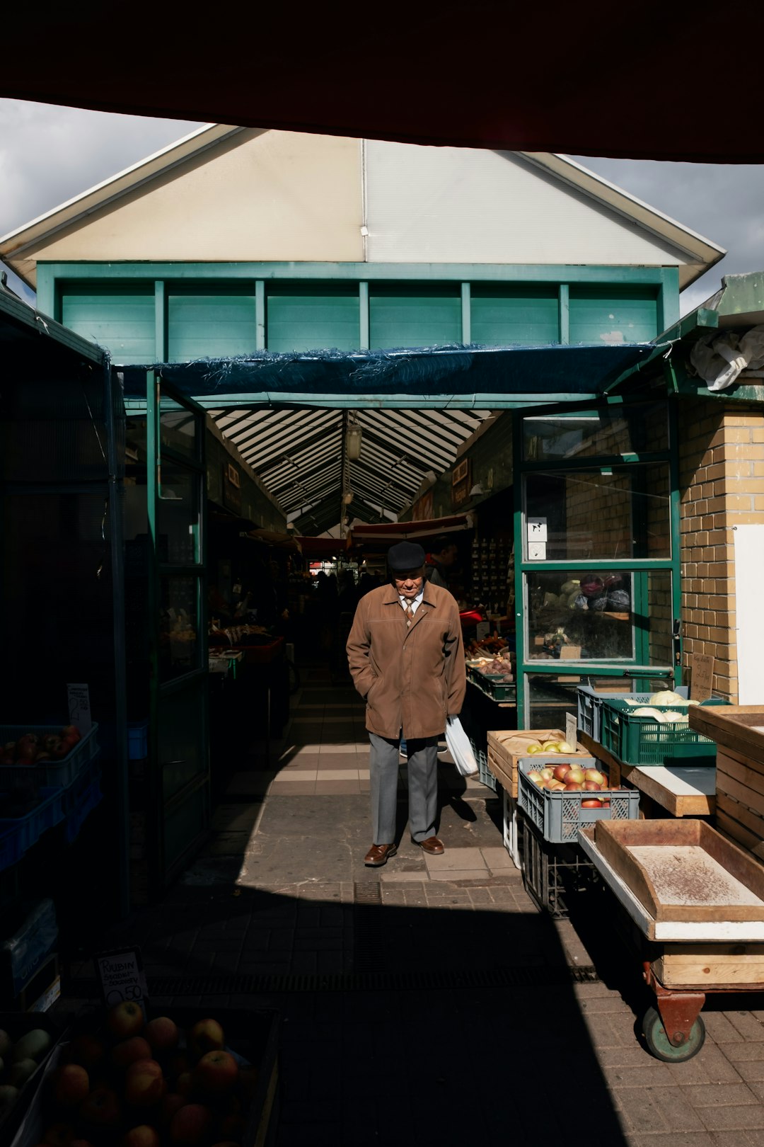 person wearing brown coat standing across white green steel arch