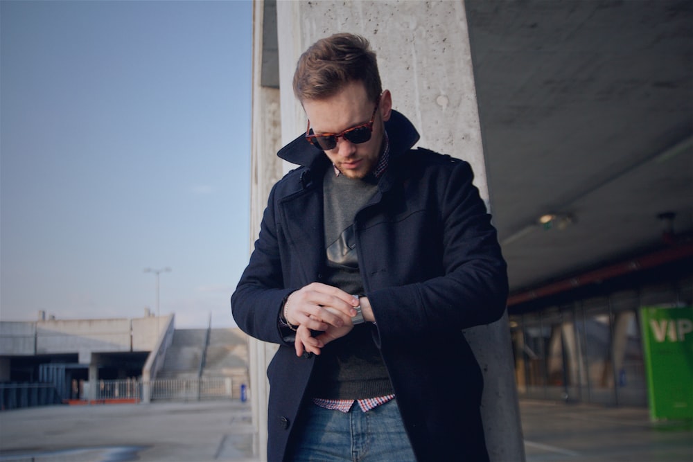 man wearing black coat looking at watch