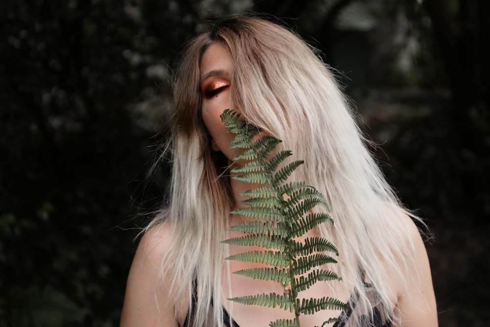 woman standing behind fern plant