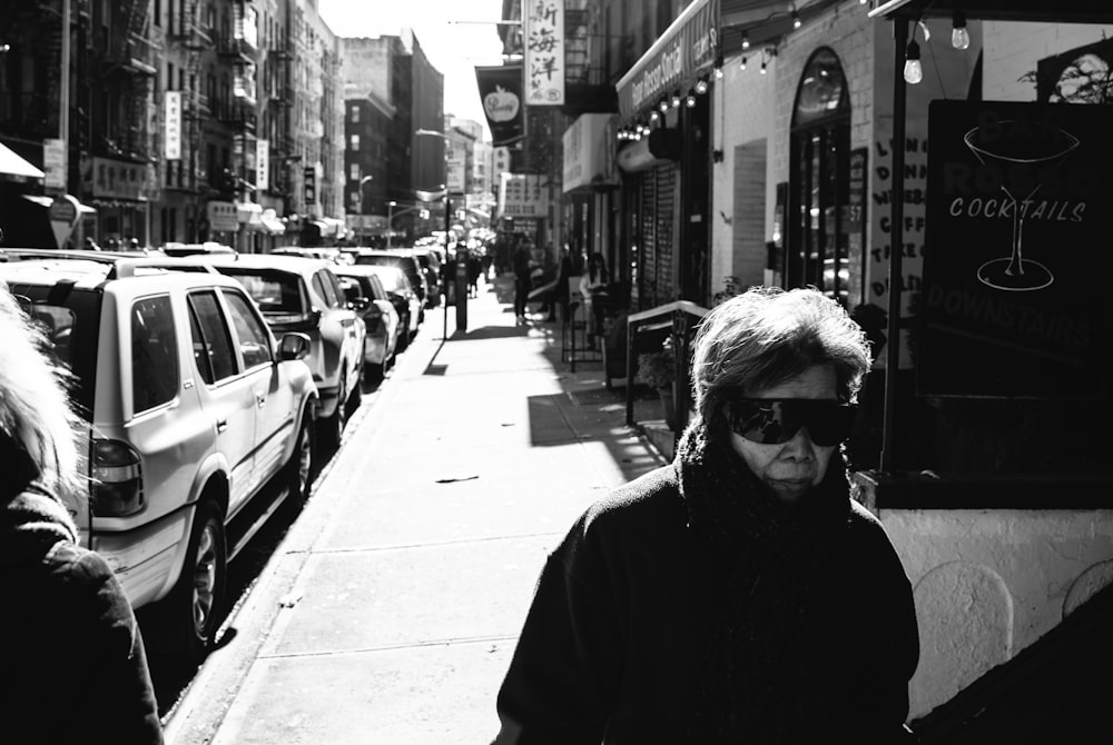uma foto em preto e branco de uma mulher andando pela rua