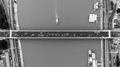 Aerial shot of a completed bridge spanning a river with vehicles crossing.