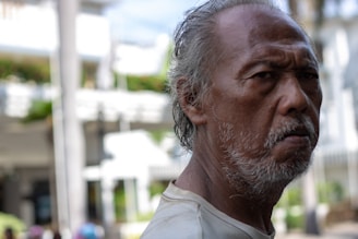 An elderly man sitting on a park bench, reflecting on life with a thoughtful expression.