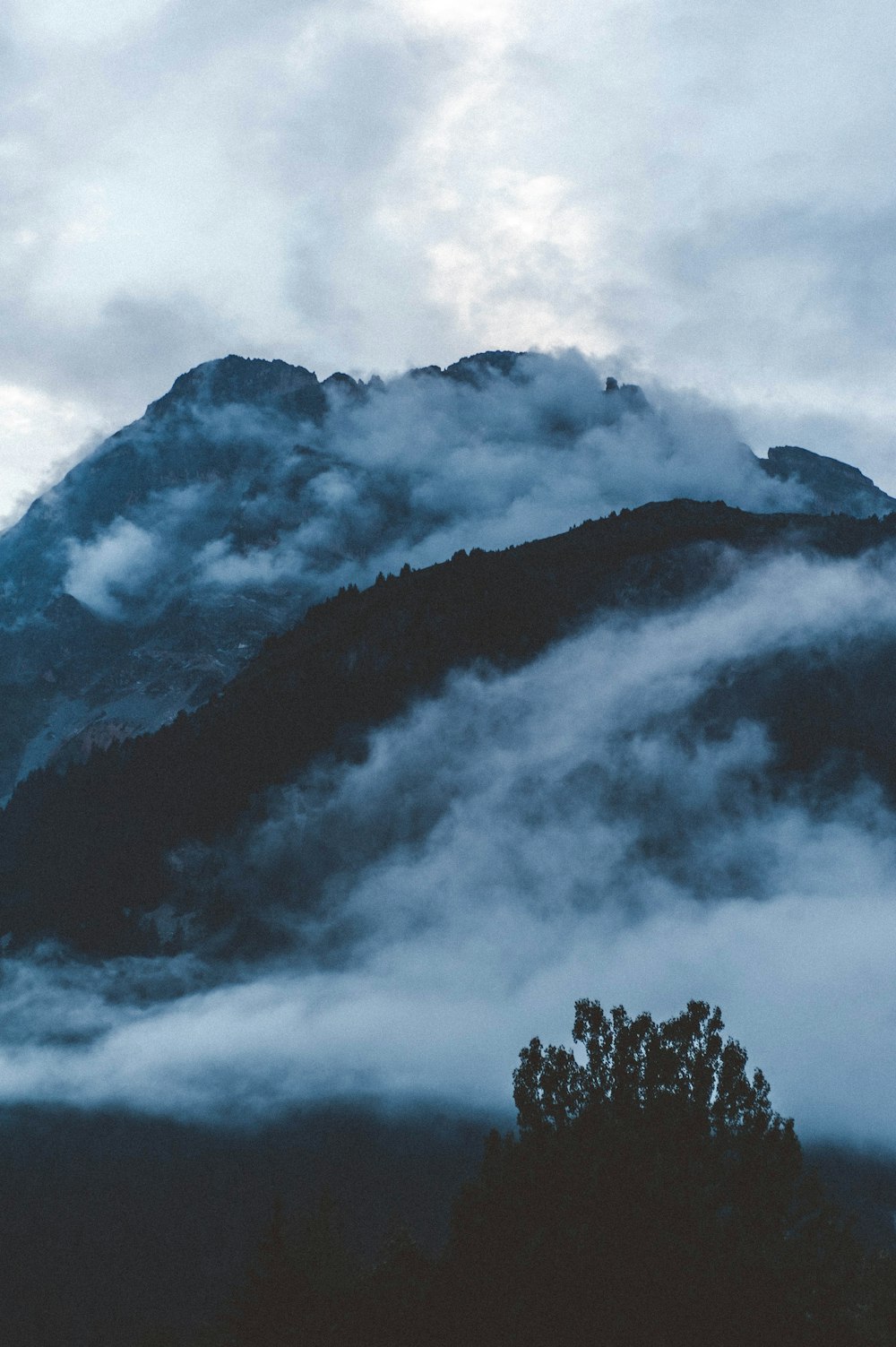 silhouette of mountain with white clouds during golden hour