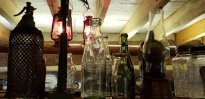 Rows of antique glassware displayed on rustic wooden shelves, glowing warmly in golden afternoon light.