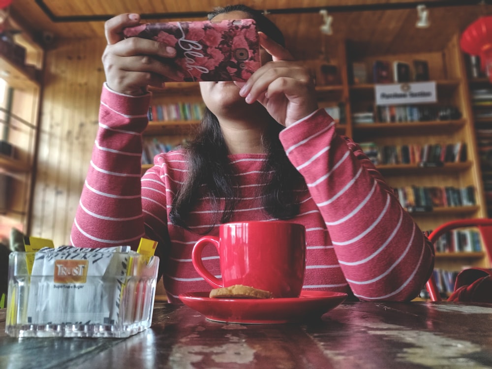 woman seated near table holding phone